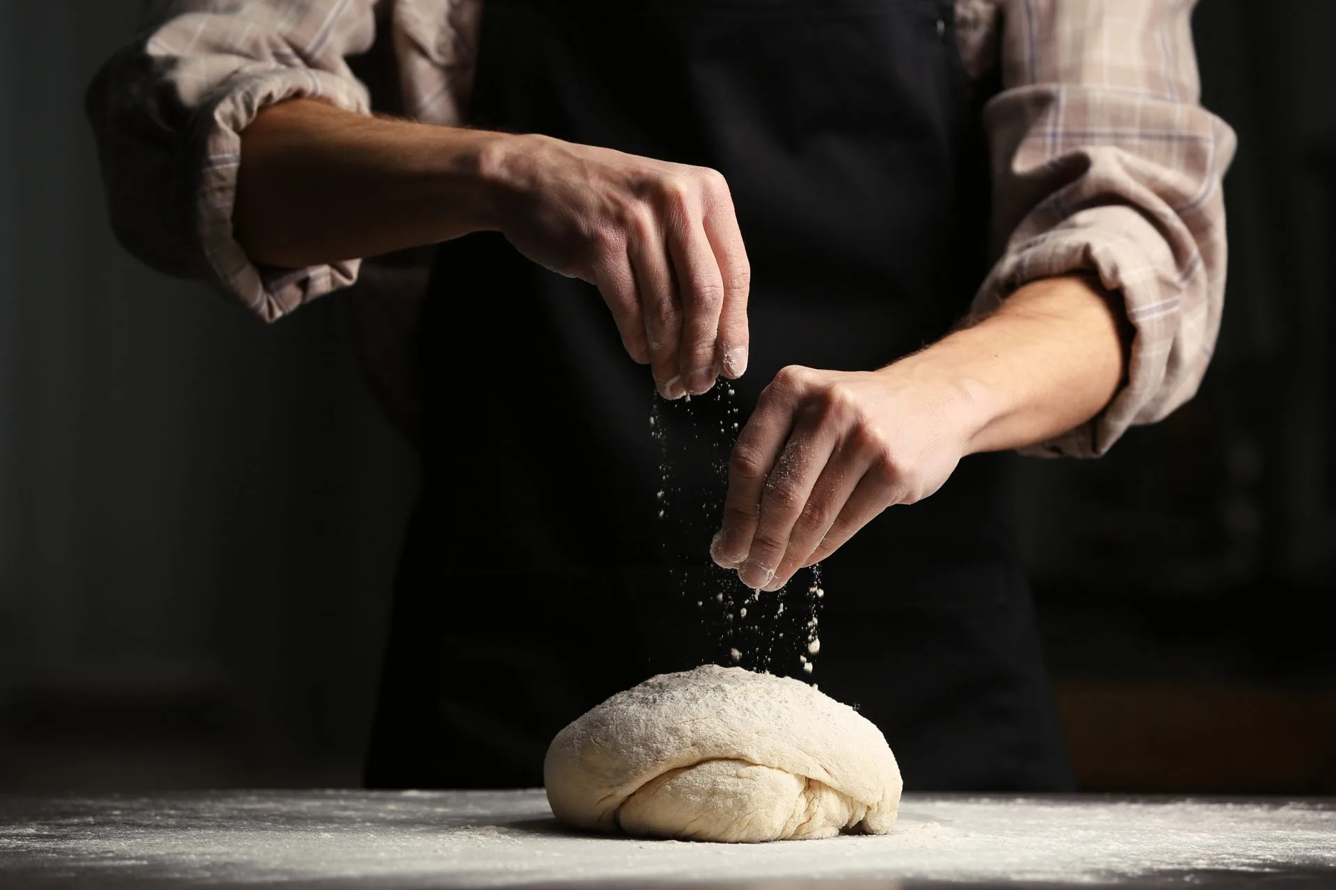 Mains de boulanger qui farine la pâte